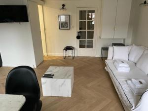 ein Wohnzimmer mit einem weißen Sofa und einem Tisch in der Unterkunft Élégant Appartement près du Musée du Louvre et du Jardin des Tuileries in Paris