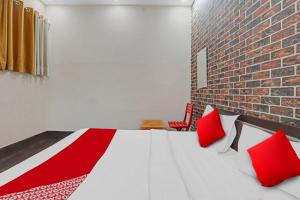 un letto con cuscini rossi in una stanza con muro di mattoni di OYO Flagship Hotel New Pacifica Grand Near Phoenix United Lucknow a Charbagh