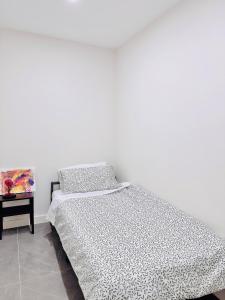 a white bedroom with a bed and a side table at Sydney Olympic Park Walk to Aquatic Centre and Stadium in Sydney