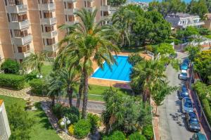 an aerial view of a resort with a swimming pool and palm trees at Palma Fiesta Apartment by Hello Homes Sitges in Sant Pere de Ribes
