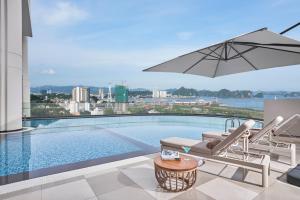 uma piscina com cadeiras e um guarda-sol num edifício em The Yacht Hotel by DC em Ha Long