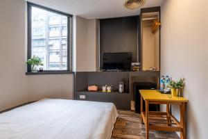 Schlafzimmer mit einem Bett, einem Schreibtisch und einem TV in der Unterkunft Guide Hotel Taipei Dadaocheng in Taipeh