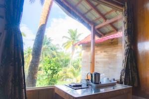 a kitchen with a large window with a view of palm trees at GRAND OCEANUS RESORT in Beadonābād