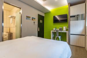 um quarto com uma cama branca e uma parede verde em Guide Hotel Taipei Dadaocheng em Taipei