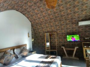 シギリヤにあるNIVADOO RESORT SIGIRIYAのベッドルーム1室(ベッド1台、壁にテレビ付)