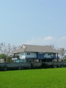 uma casa com um campo verde em frente em กิติ์ชาวิว วิลล่า em Ban Nang Lae