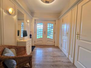 einen Flur mit einem Korbstuhl und zwei Fenstern in der Unterkunft Ferienhaus Cäcilienhof West in Kampen