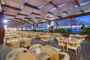 a restaurant with tables and chairs and a view of a city at Alan Xafira Deluxe Resort & Spa-ULTRA ALL INCLUSIVE in Alanya
