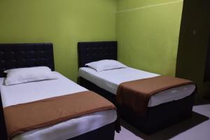 two beds in a room with green walls at OYO 93764 Homestay Citra in Kendari