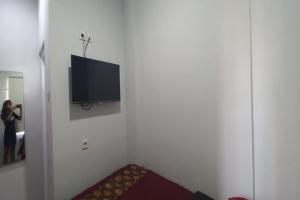 Eine Frau fotografiert ein Zimmer mit einem TV an der Wand in der Unterkunft OYO 93769 Setia Budi Guest House 2 in Sragen