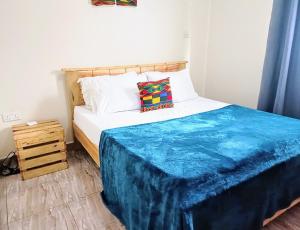Un dormitorio con una cama con una manta azul. en Amaryllis blue,8mins source to River Nile,secure, peaceful, central great location, en Jinja