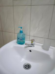 a bottle of soap sitting on top of a white sink at Amaryllis blue,8mins source to River Nile,secure, peaceful, central great location in Jinja