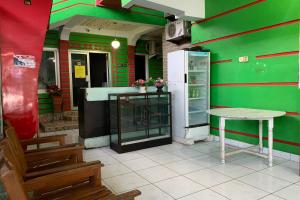 Grünes Zimmer mit einem Tisch und einem Kühlschrank. in der Unterkunft OYO 93770 Pondom Danu 77 in Kendari