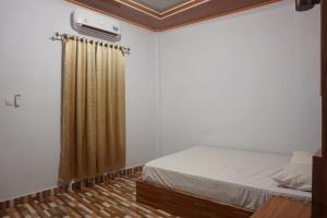ケンダリにあるOYO 93770 Pondom Danu 77のベッドルーム(ベッド1台、カーテン付)