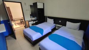 Rantau的住宿－OYO 93775 Nilam Guest House，酒店客房,设有两张床和镜子