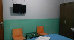 um quarto com uma mesa e duas cadeiras e uma televisão na parede em OYO 93775 Nilam Guest House em Rantau