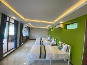 two beds in a room with a green wall at Kep Orchid Boutique Resort in Kep
