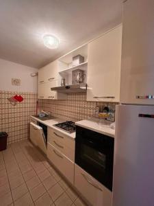 La cuisine est équipée de placards blancs et d'un four avec plaques de cuisson. dans l'établissement Residenza Rovetta, à Rovetta