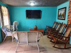 a living room with chairs and a flat screen tv at House for 5 with vehicle included in Roatan in Coxen Hole