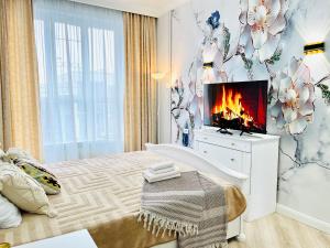 a bedroom with a bed with a tv and a fireplace at Nissibeli in Almaty