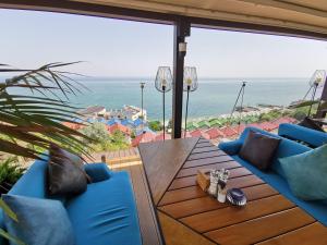 patio ze stołem i niebieskimi krzesłami oraz oceanem w obiekcie Подвійний котедж з терасою біля моря Совіньон w Odessie