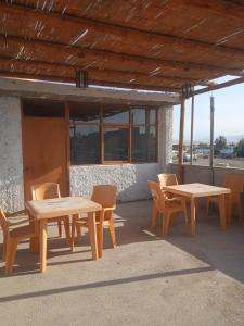 een groep houten tafels en stoelen voor een gebouw bij HOSPEDAJE PARACAS SUR in Paracas