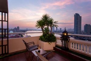 balcón con 2 sillas y vistas a la ciudad en Ramada Plaza by Wyndham Bangkok Menam Riverside en Bangkok