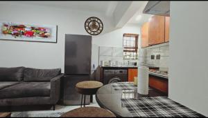 un salon avec un canapé et une cuisine dans l'établissement Bryanston Guest Cottage, à Johannesbourg