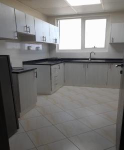 a kitchen with white cabinets and a black counter top at AL ALKEEM HEIGHTS in Ras al Khaimah