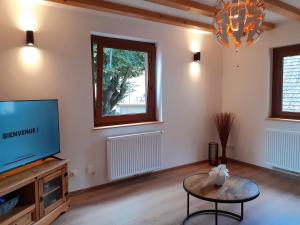 een woonkamer met een tv en een tafel bij Gîte de la Muse in Rouffach