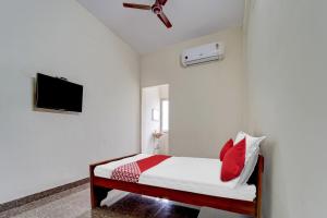 a bedroom with a bed with red pillows and a ceiling fan at OYO Flagship V A S Lodge in Punjai Puliyampatti