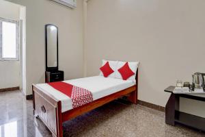 a small bed with red and white pillows in a room at OYO Flagship V A S Lodge in Punjai Puliyampatti