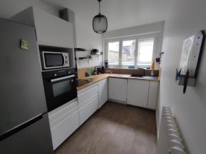 a small kitchen with white cabinets and a microwave at Appartement 2 Chambres INDIaNA Hyper centre in Vitré