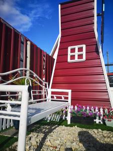 Red Triangle Cottage Roomstay في كامبونغ كيممان: مقعد امام مبنى احمر به ورد
