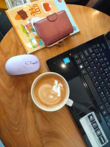 a cup of coffee on a wooden table next to a keyboard at Studio Healing Sayana Apartment in Tambun-lobangbuaja