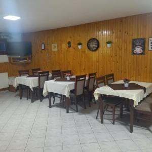 a dining room with tables and chairs and a tv at Penzion Helena in Stará Lesná