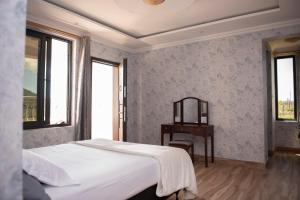 a bedroom with a bed and a table and windows at Mara Meguarra Sanctuary in Ololaimutiek