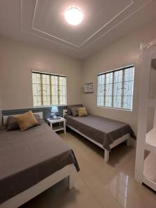 1 dormitorio con 2 camas y 2 ventanas en Japandi Home C - Fully Aircon, WIFI, Hot shower, 24hGuard, Center, near Malls, en General Santos