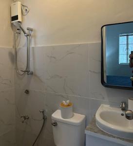 ein Badezimmer mit einem WC, einem Waschbecken und einem Spiegel in der Unterkunft Japandi Home C - Fully Aircon, WIFI, Hot shower, 24hGuard, Center, near Malls in General Santos