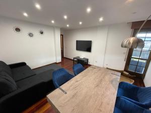 a living room with a black couch and blue chairs at Alojamiento Alameda in Redondela