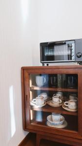 a microwave oven with plates and cups in a cabinet at Murmure　6人家族や友人向け　ペット可 in Tsumagoi
