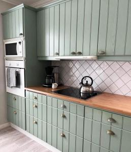 a kitchen with green cabinets and a tea kettle on the counter at Charming cottage in Forsa, Hudiksvall with lake view in Hudiksvall