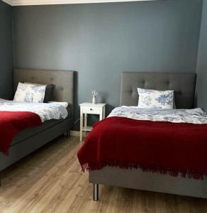 a bedroom with two beds with red sheets and a table at Charming cottage in Forsa, Hudiksvall with lake view in Hudiksvall