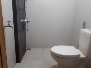 a white bathroom with a toilet and a shower at OYO 93710 Bidara Guest House Syariah in Mojokerto