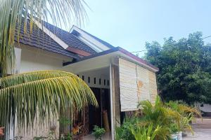 庫塔的住宿－SPOT ON 93724 Songgong Homestay，前面有棕榈树的房子