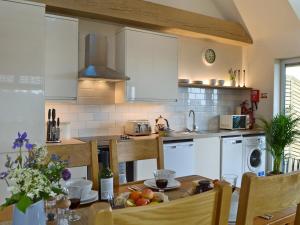 uma cozinha com uma mesa e uma cozinha com armários brancos em Poachers View-ukc2488 em Mountfield
