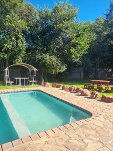 a swimming pool in a yard with a picnic table and benches at De Prince Lodge in Vereeniging