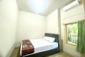 a small bedroom with a bed and a window at SPOT ON 93717 Nayus Homestay Syariah 4 in Yogyakarta