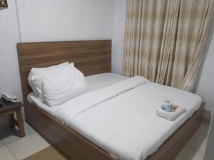 a bedroom with a bed with white sheets and a pillow at Mid Way Best Hotel in Lagos