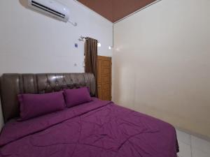 a bed with purple sheets in a room at OYO 93714 Guest House Gembul Syariah in Jambi
